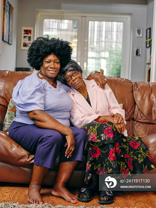 Mature woman embracing senior mother on sofa