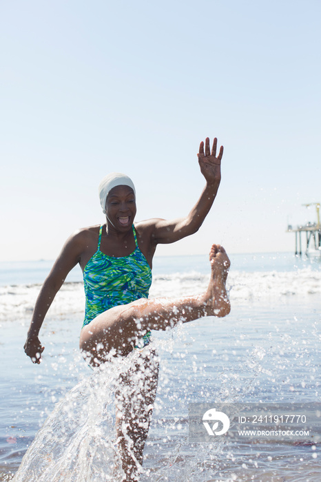 Playful woman splashing in sunny ocean