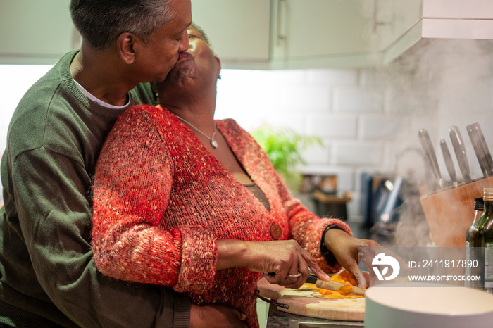 Senior couple preparing food in kitchen and kissing