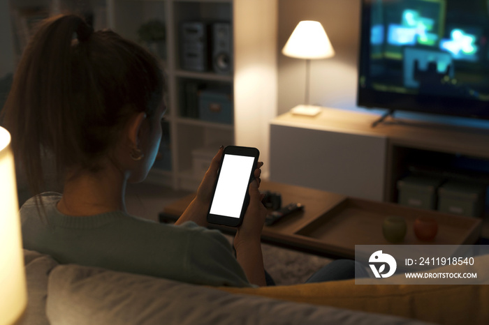 Teenager sitting on the couch and using her smartphone