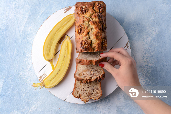 Woman taking slice of tasty banana bread from board