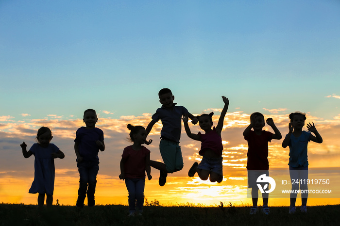 Happy kids silhouettes on sunset background