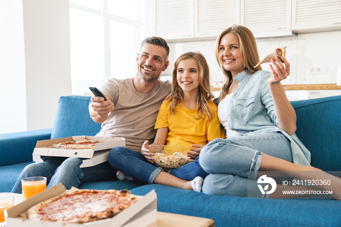 一家人一边看电视一边吃爆米花和披萨的照片