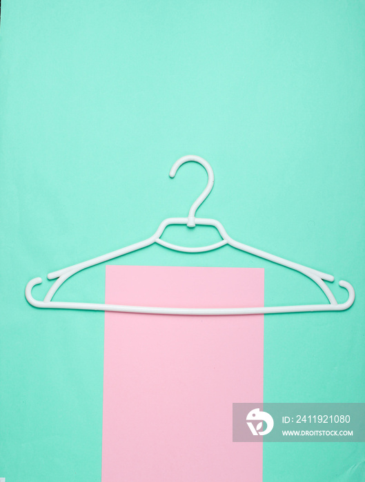 White plastic hanger on blue pink background. Top view