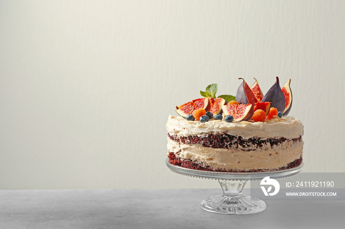 Delicious creamy cake with figs and berries on light background