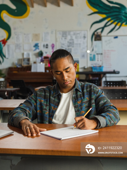 Concentrated Native boy writes on a full page in his notebook during class