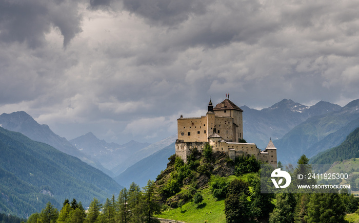 瑞士恩加丁山谷一座山丘上的城堡，有树木和草地，有山脉和城堡