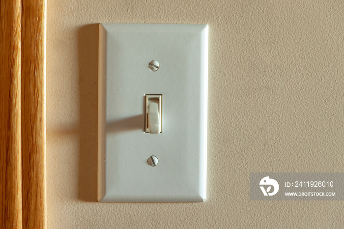 An old North American light switch on a wall near a doorway