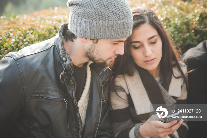 Young couple reading smartphone texts in park