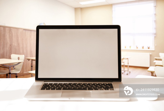 Modern laptop with blank screen on table in classroom