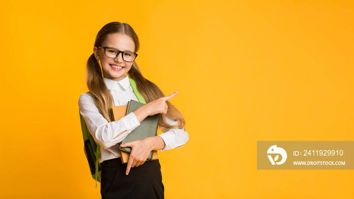 Schoolgirl Pointing Finger At Empty Space For Text, Studio Shot