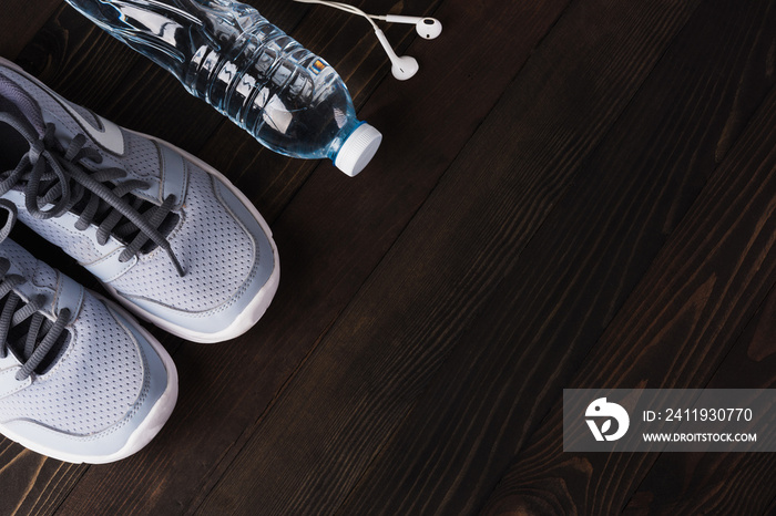 Top view of pair sports shoes, headphones and water bottle on black wood table background, Gray snea