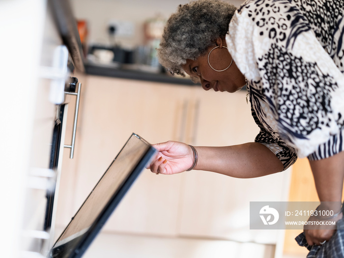 Mature woman opening oven door