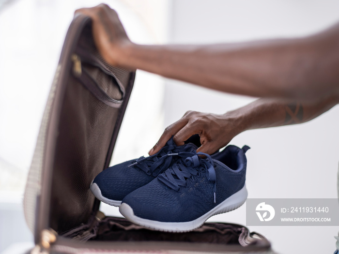 Close-up�of person putting sport shoes into suitcase