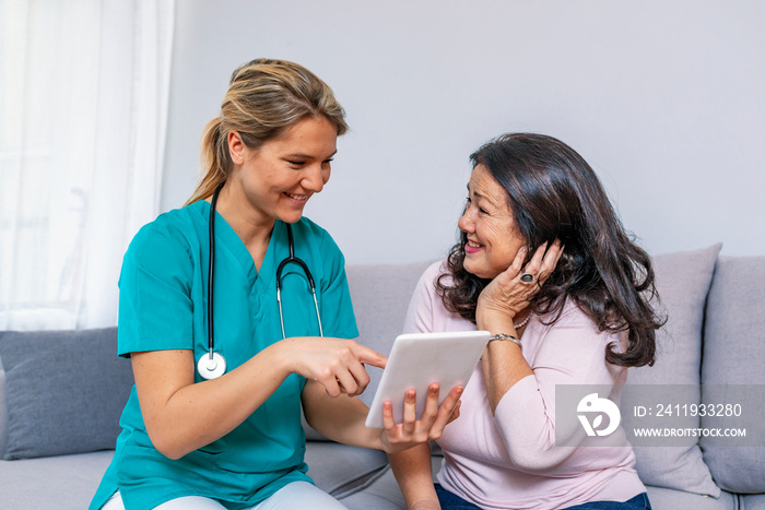 Happy young caregiver and senior woman using digital tablet together