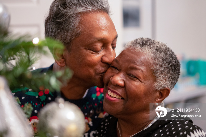 Senior couple kissing by Christmas tree