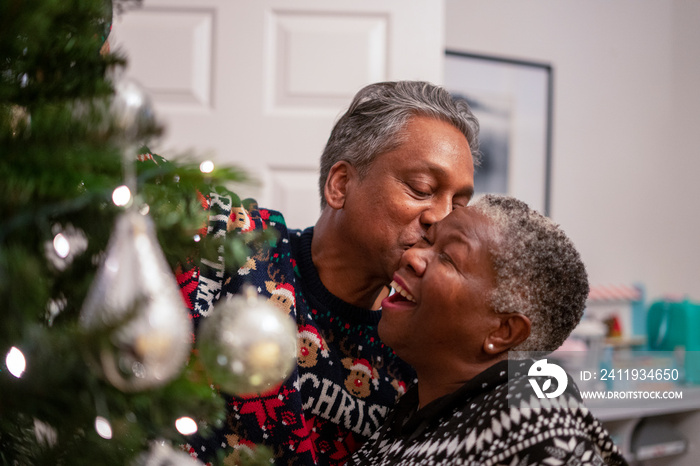 Senior couple kissing while decorating Christmas tree