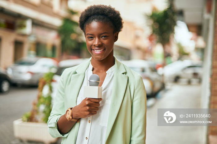 Young african american reporter woman using microphone at the city