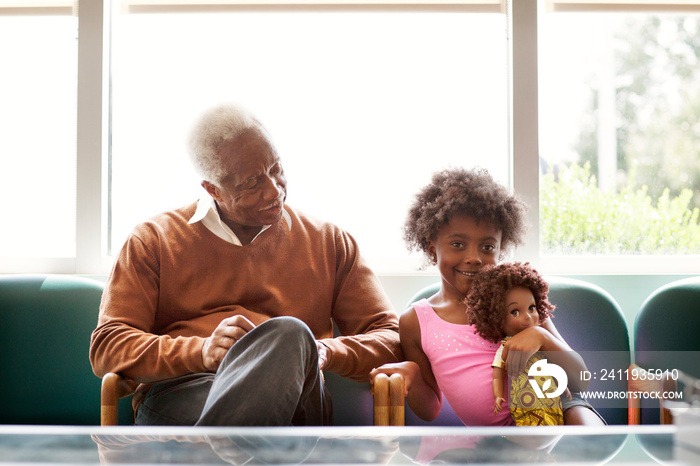 Girl (4-5) and grandfather sitting side by side in armchairs