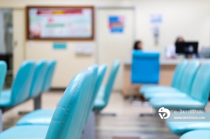 医院候诊室里的蓝色空椅子，护士台背景模糊。