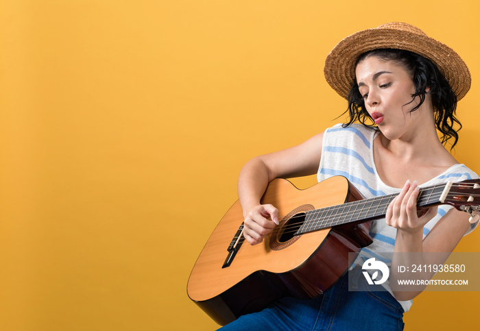 Young woman with a guitar on a yellow background