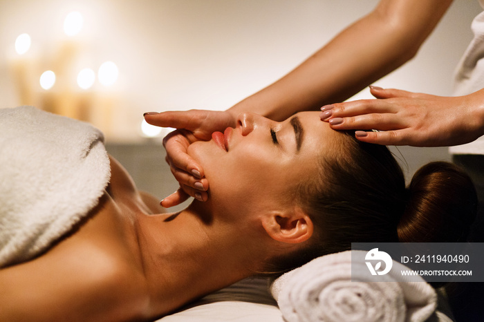 Woman enjoying anti aging facial massage in atmospheric spa