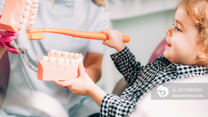 Little girl at dental clinic, learning how to brush teeth correctly