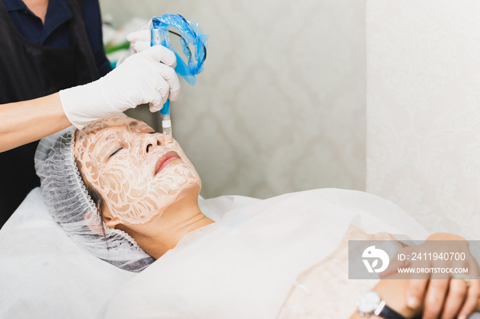 Woman having stimulating facial treatment at professional clinic.