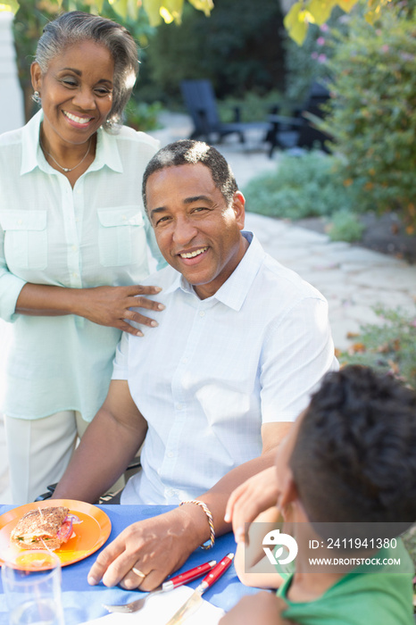 Portrait smiling senior couple eating lunch on patio with grandson