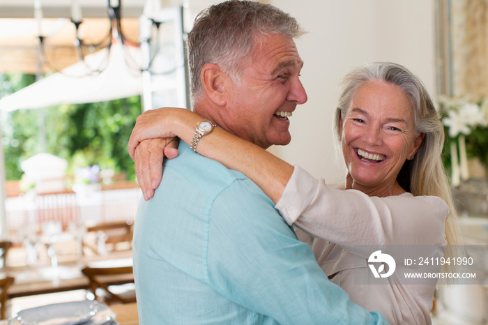 Portrait happy senior couple hugging in kitchen