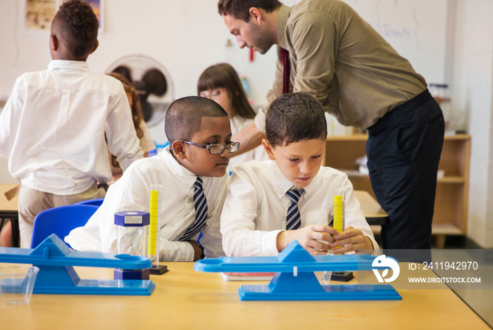 Portrait of two schoolboys (8-9, 10-11) using laboratory glassware in classroom