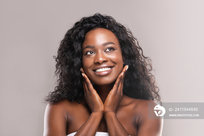 Young black woman applying moisturizer cream on her face