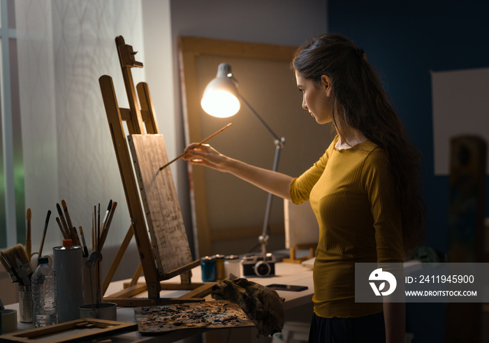 Young creative painter working with a lamp in the studio