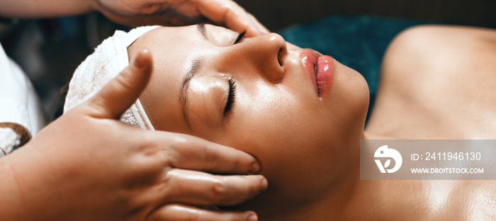 Caucasian spa worker finishing a facial massage session at the spa with a beautiful woman