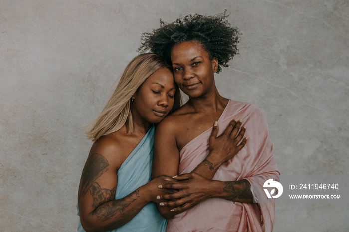 2 African American women posing together holding hands faces touching