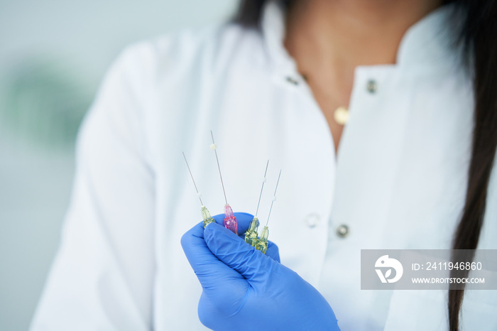 Beautician holding polydioxanone thread for lifting over light background