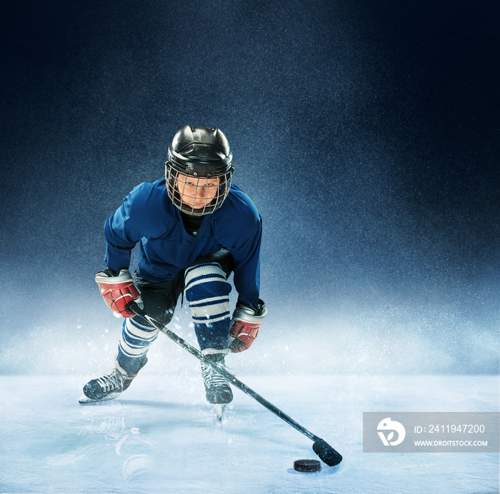 小男孩在竞技场上打冰球。一名身穿制服的冰球运动员，蓝色背景上有装备。