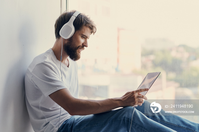 Cheerful man sitting on the windowsill technologies