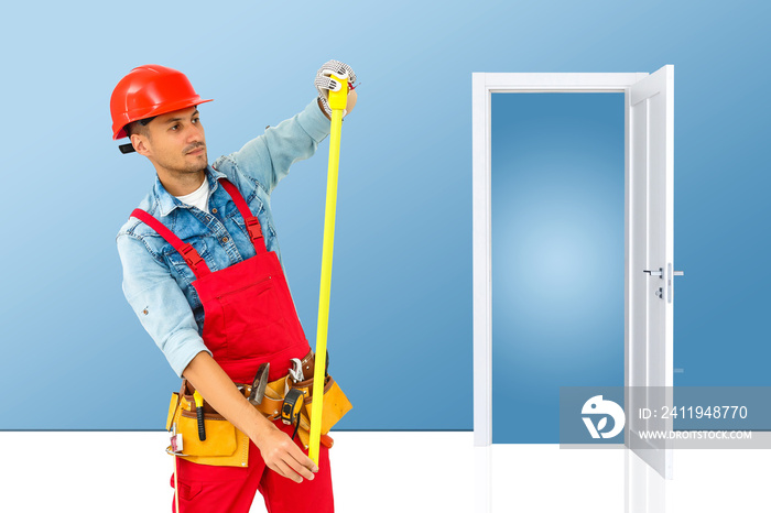 Young handyman installing a white door with an electric hand drill in a room