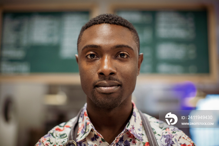 Close-up portrait of confident male barista standing in coffee shop