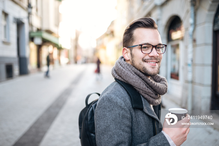 Young entrepreneur with takeaway coffee in the city street.