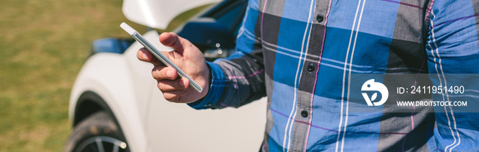 Unrecognizable young man with broken down car calling by mobile phone