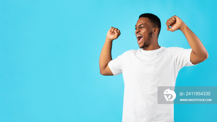 Millennial Guy Shouting Loudly Clenching Fists Over Blue Background, Panorama