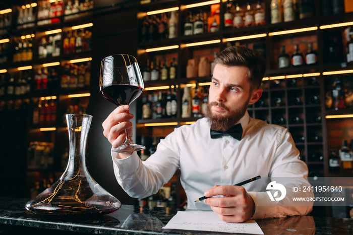 Young handsome man sommelier tasting red wine in cellar.