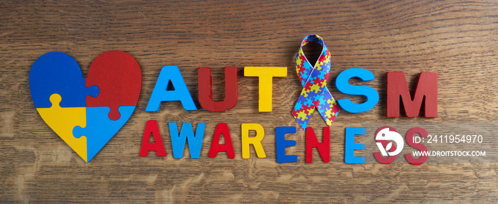 Autism awareness. Autism awareness ribbon, heart and word autism on wooden background background.