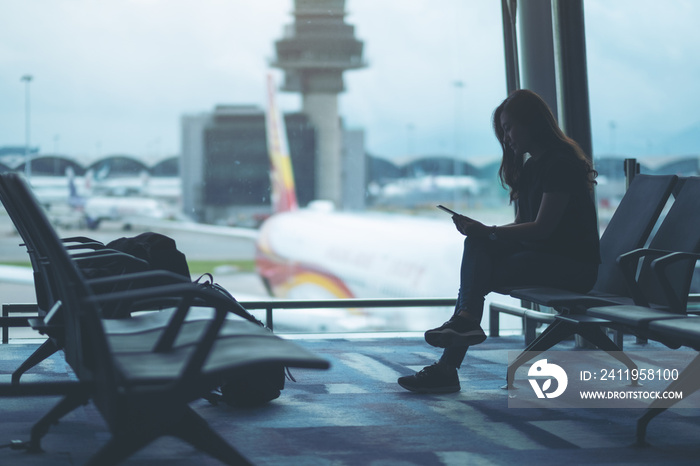 A woman traveler using mobile phone while sitting in the airport