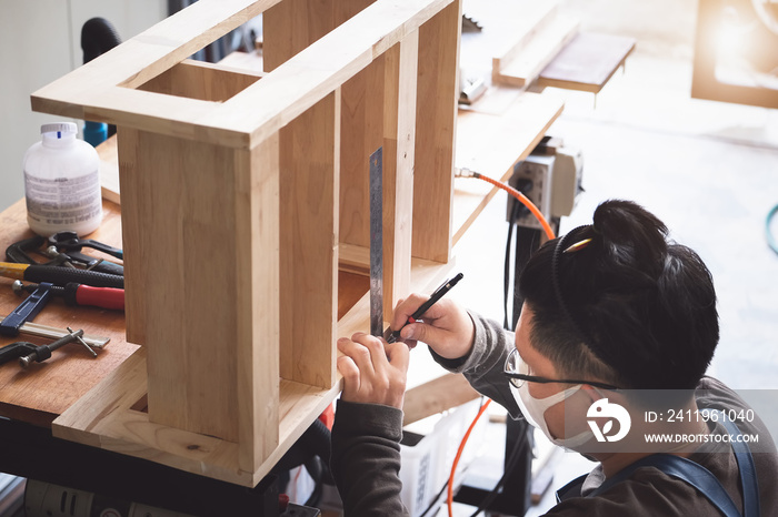 A carpenter measures the planks to assemble the parts, and build a wooden table for the customer