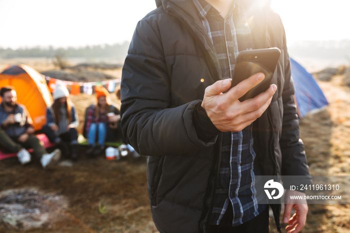 Man outside in free alternative vacation camping over mountains using mobile phone chatting.