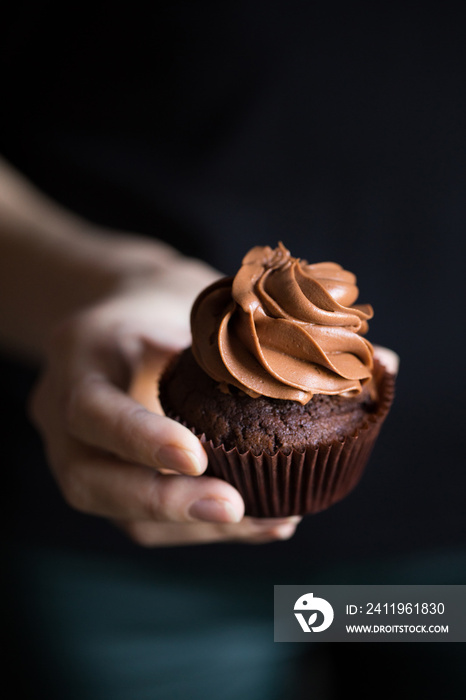 hand with chocolate cupcake