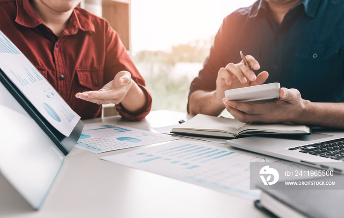 Two business people are calculating earnings financial costs of the company on desk at the office ro